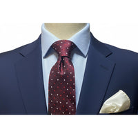 Burgundy small square tie White and Red worn with a navy suit and white pocket square, showcasing elegance and style.