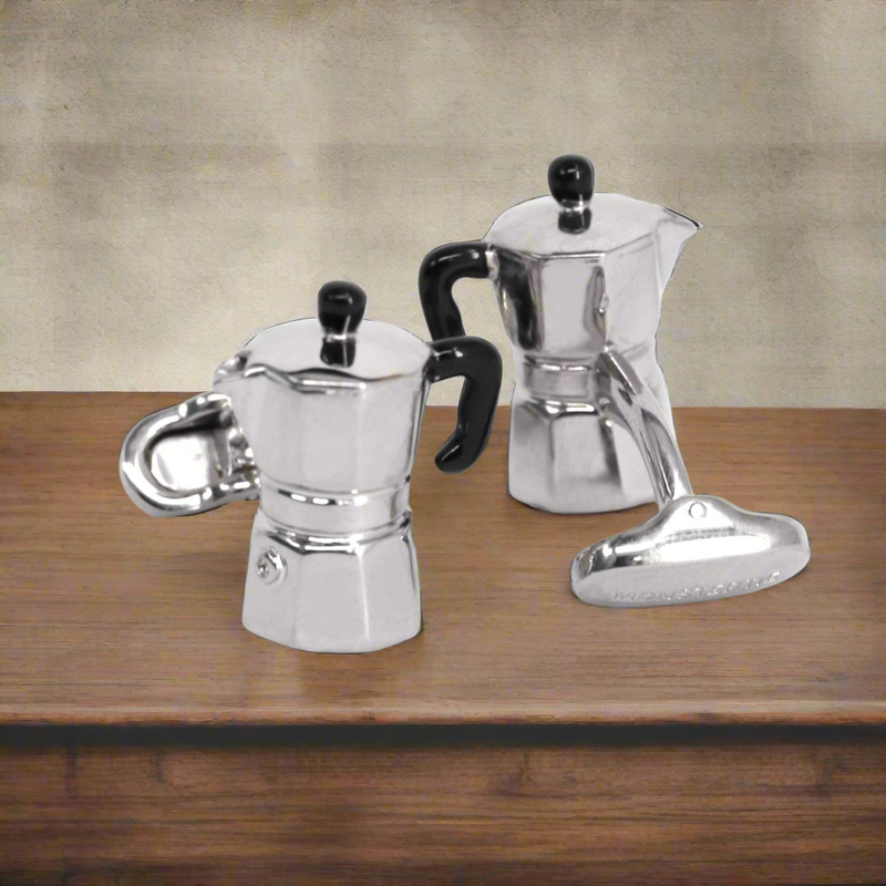 Two silver espresso pots with black handles on a wooden surface.