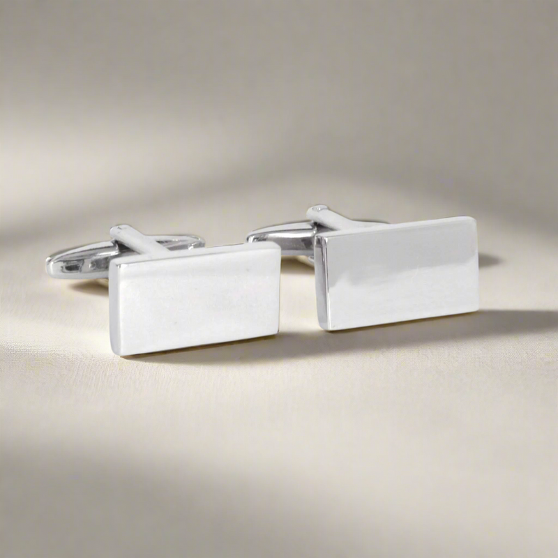 Pair of silver rectangular cufflinks on a light background