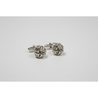 Silver knot cufflinks on a light gray background