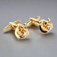 Gold knot cufflinks on a gray background