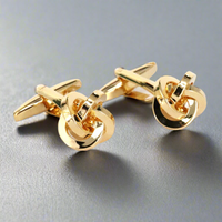 Gold knot cufflinks on a gray background