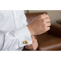 Gold knot cufflinks on a gray background