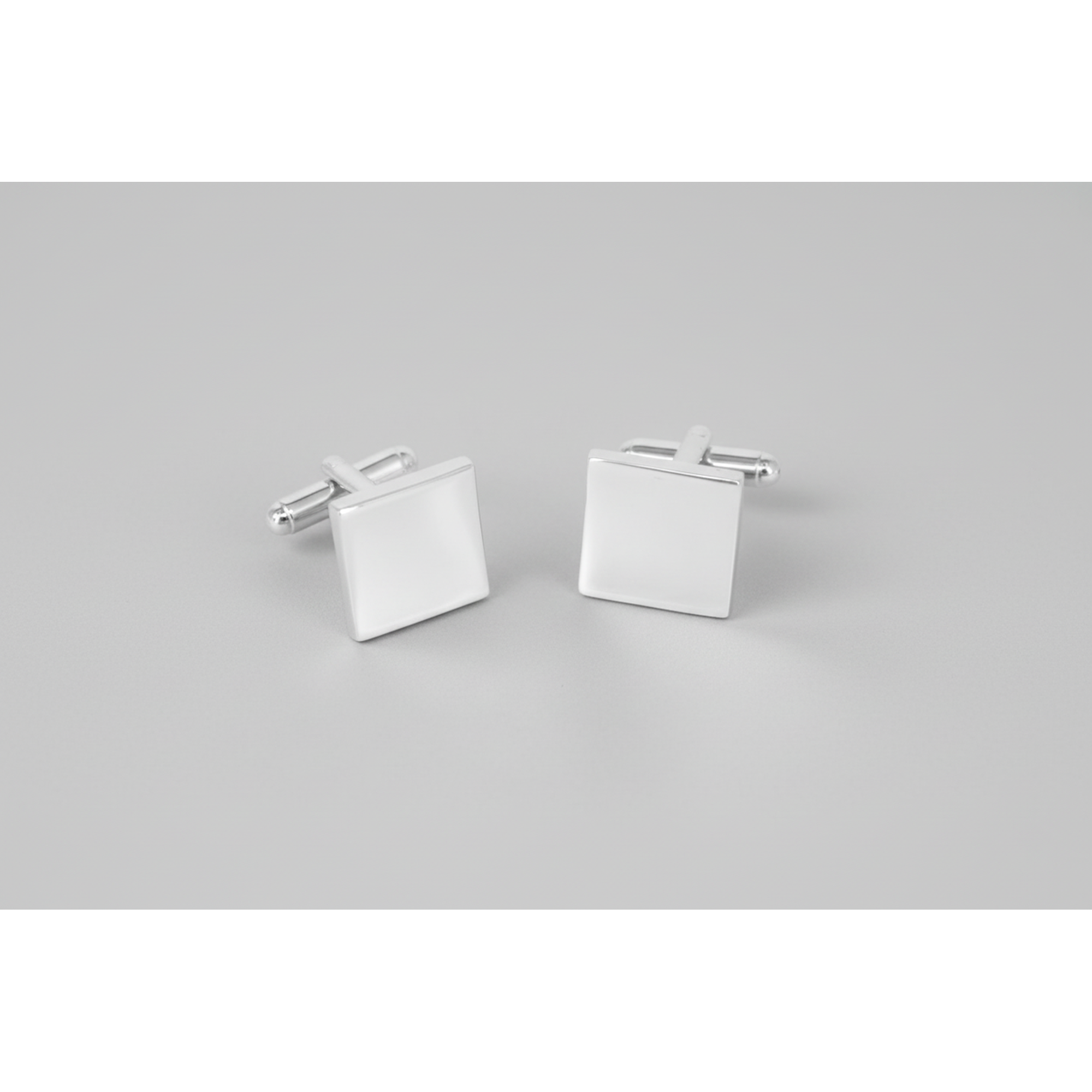 A pair of silver plain square thin cufflinks with T-bar back closure on a grey background.