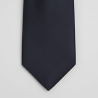 A close-up of a solid black necktie tip against a plain white background.
