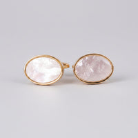 A pair of oval gold cufflinks with white mother of pearl accents on a white background.
