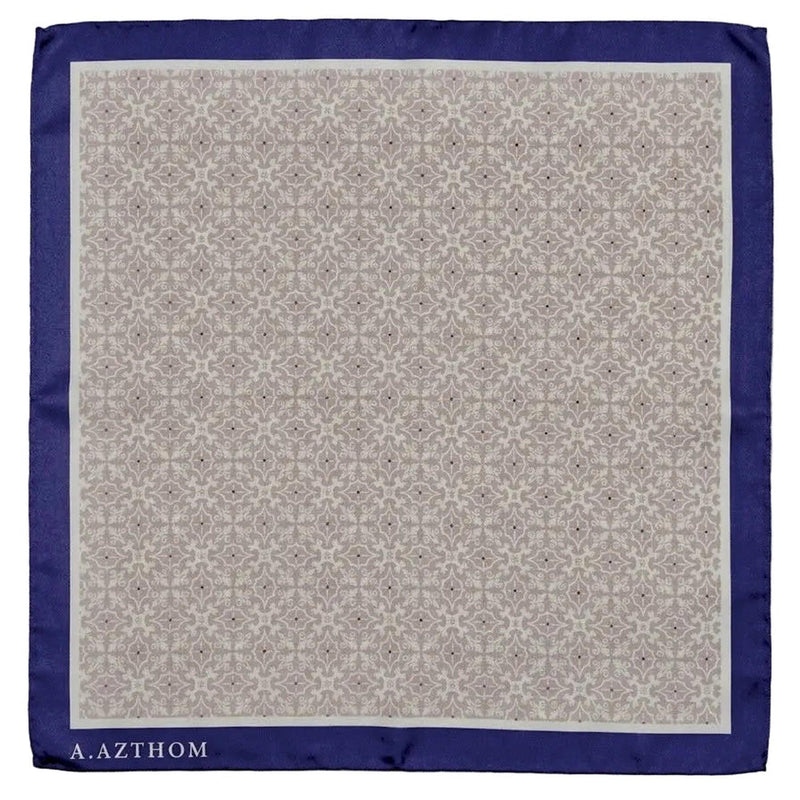 A square silk pocket square by A. Azthom, featuring a beige and brown geometric damask pattern in the center, a solid navy blue border, and the brand name printed in white at the bottom left corner.