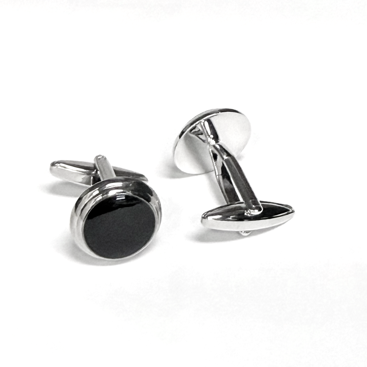 Silver cufflinks with black circular centers on a white background