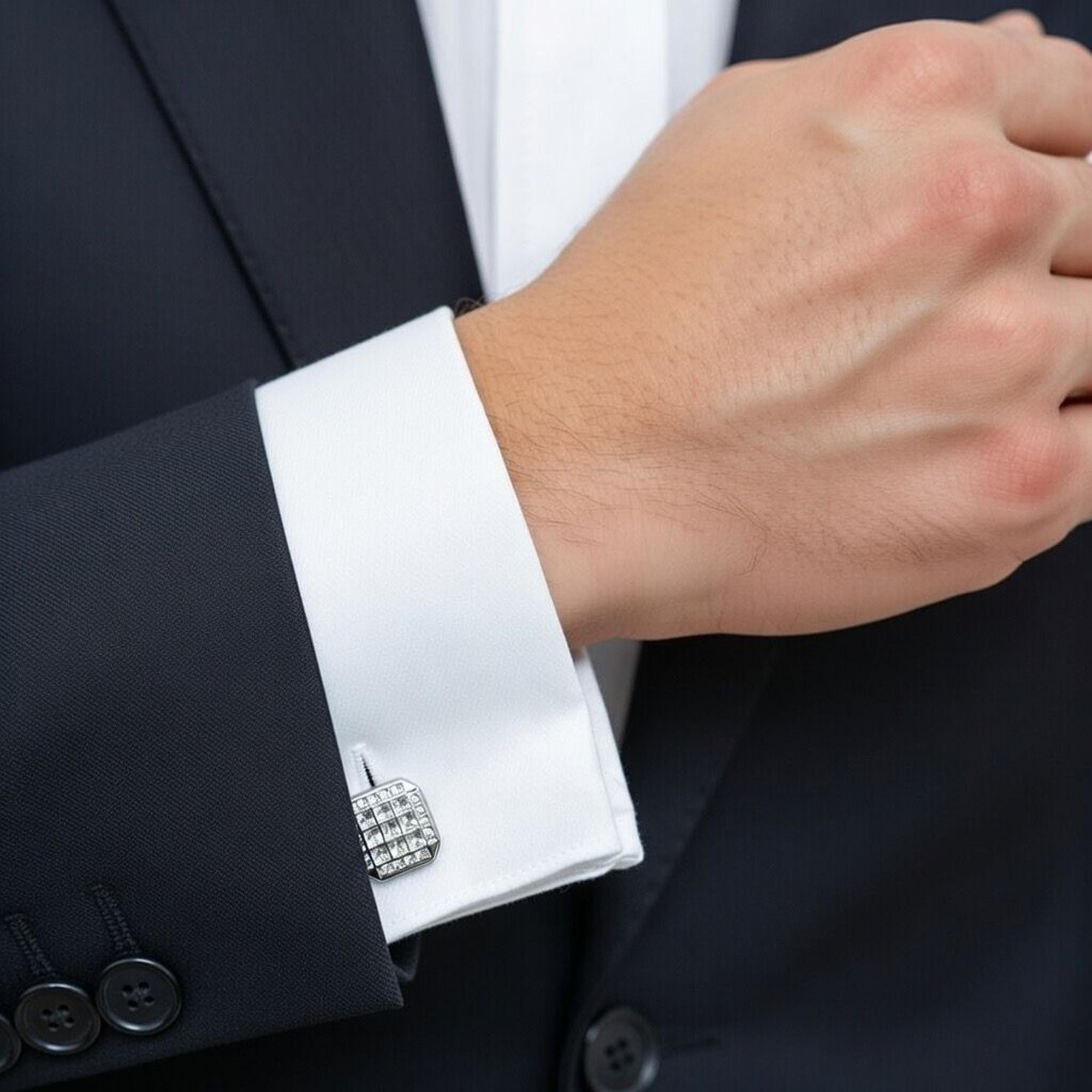 A close-up of a hand wearing crystal square silver cufflinks, showcasing elegance and style.