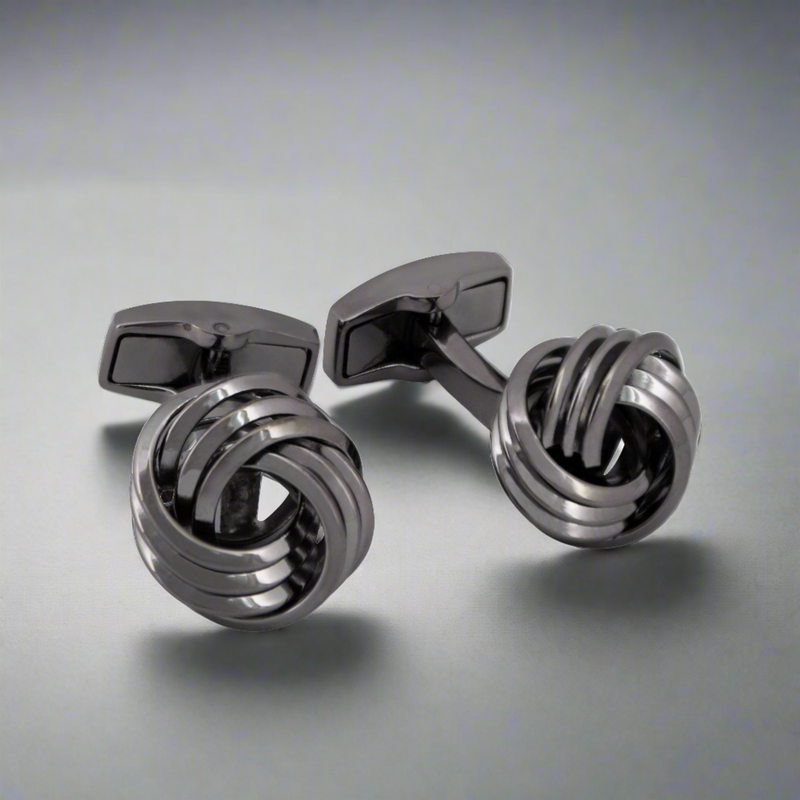 A pair of gunmetal-plated copper alloy cufflinks with a twisted knot design on a light background.