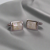 Pair of rectangular cufflinks with mosaic design on a gray fabric background
