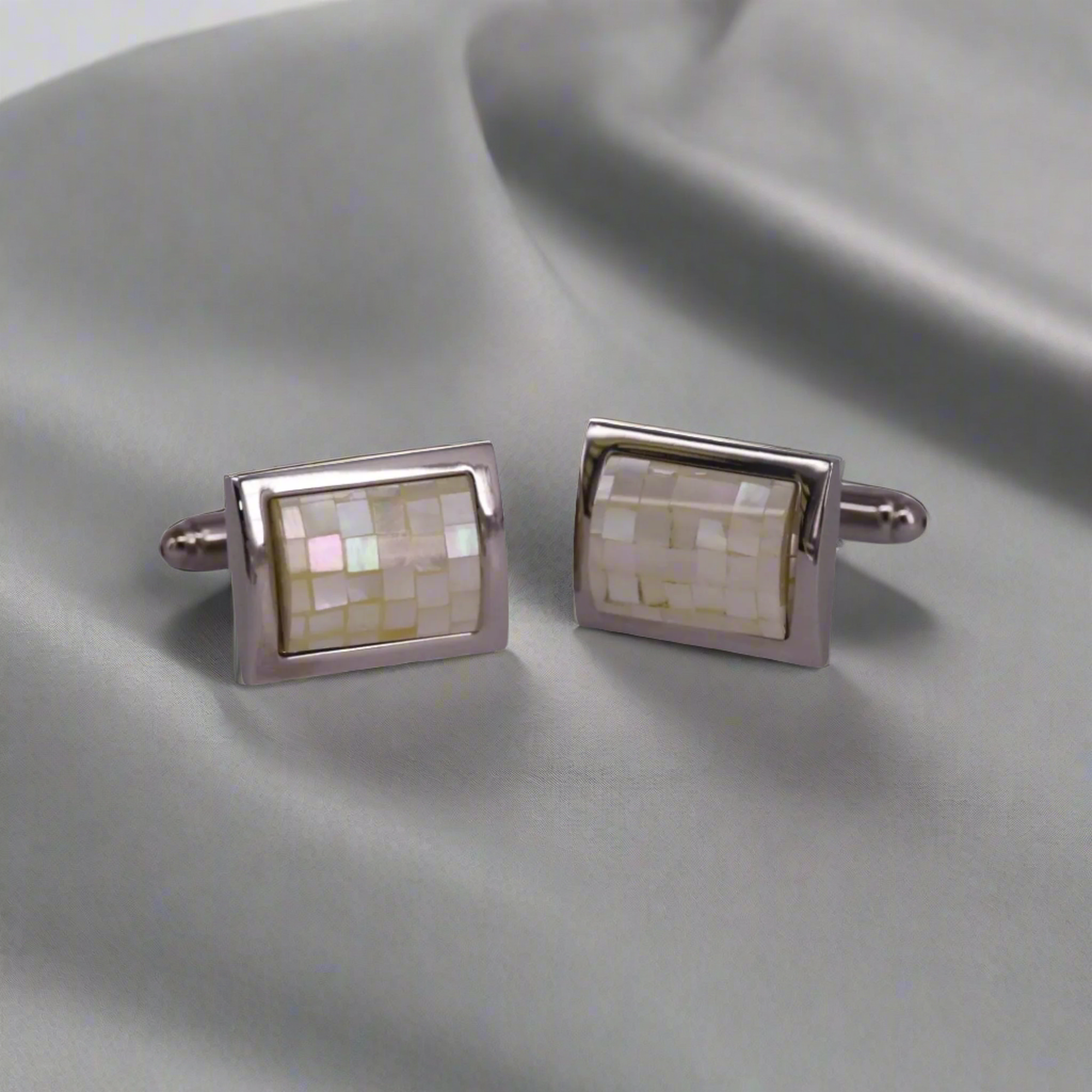 Pair of rectangular cufflinks with mosaic design on a gray fabric background