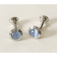 A pair of silver-toned cufflinks with oval light blue cateye, displayed on a clean off-white background.