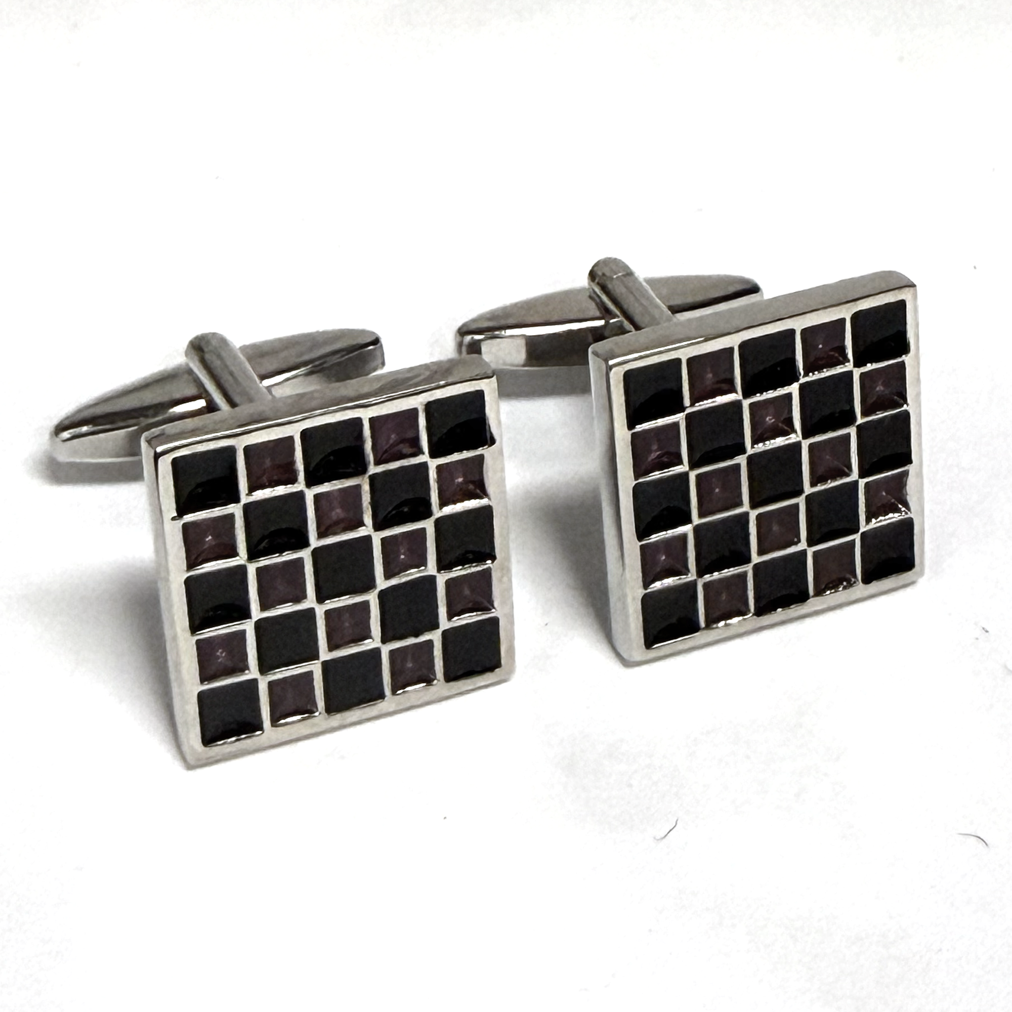 Pair of square cufflinks with black and silver checkered pattern on a white background